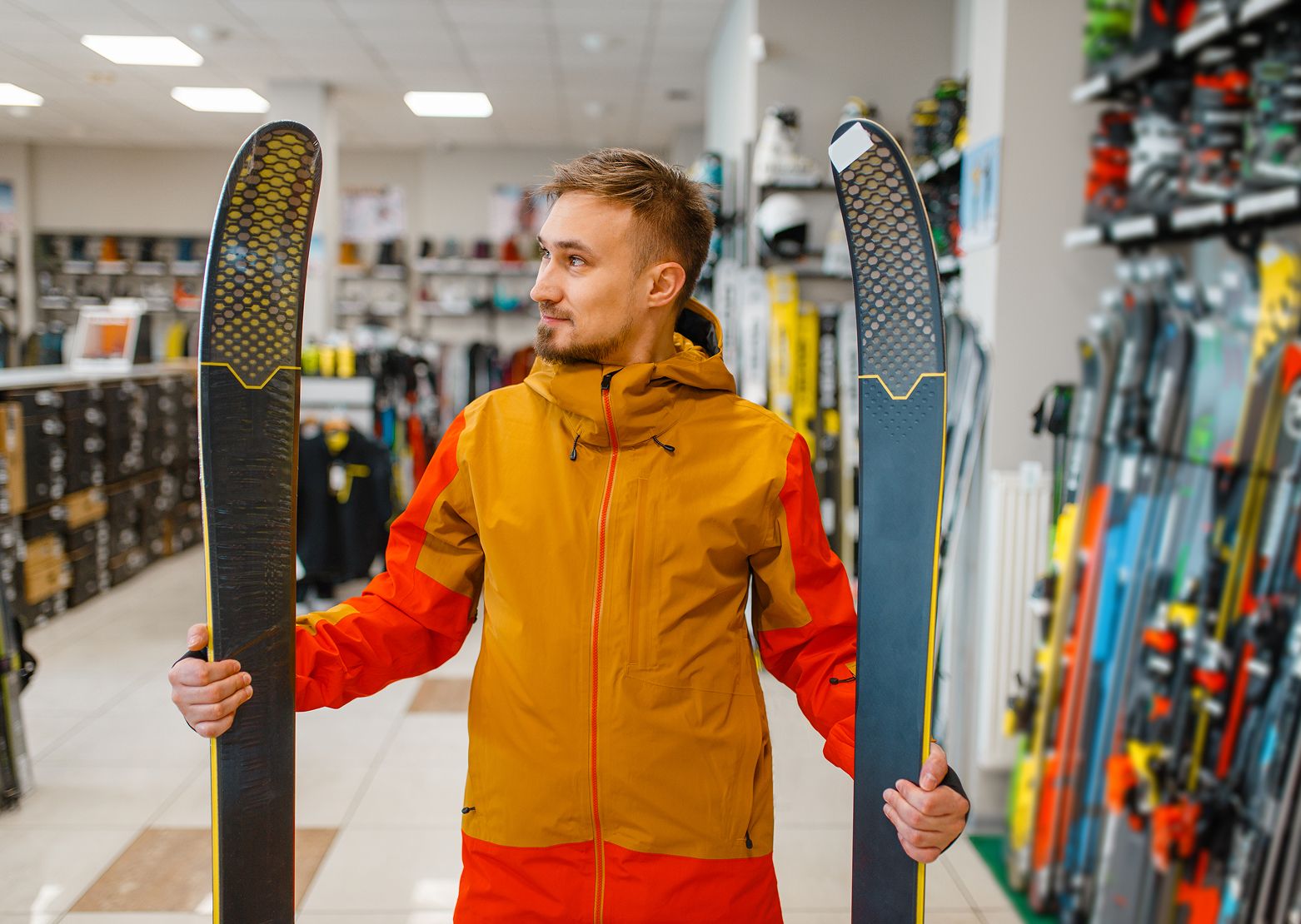 Mann im Skiverleih hält ein Paar Ski in den Händen
