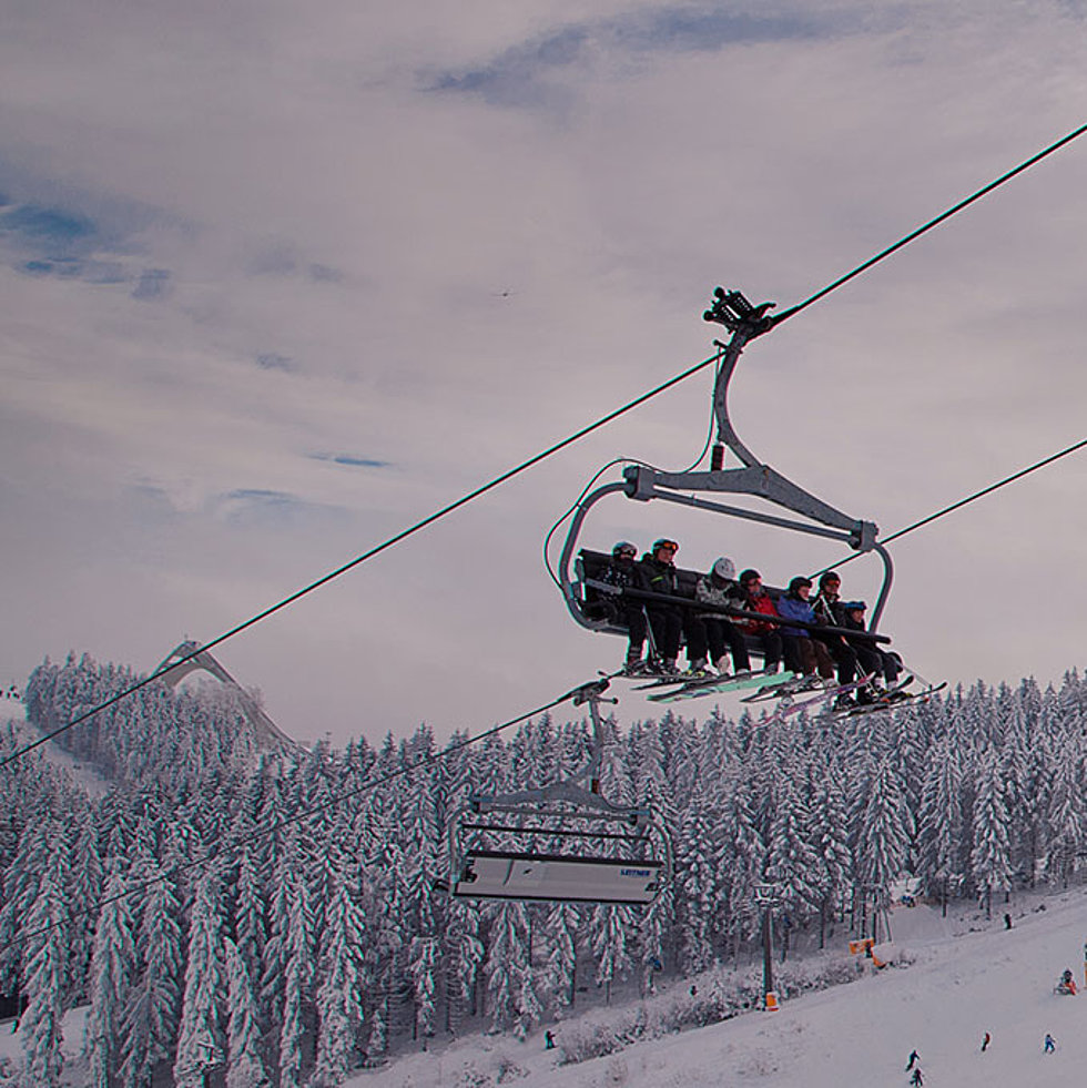 Sessellift mit Wintersportlern über verschneiten Hängen in Winterberg